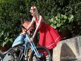 Cute blonde enjoys posing next to a bike